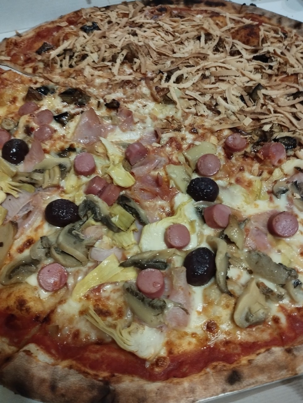 Una pizza appena sfornata da Vulcanello, con salumi, funghi, carciofi e olive